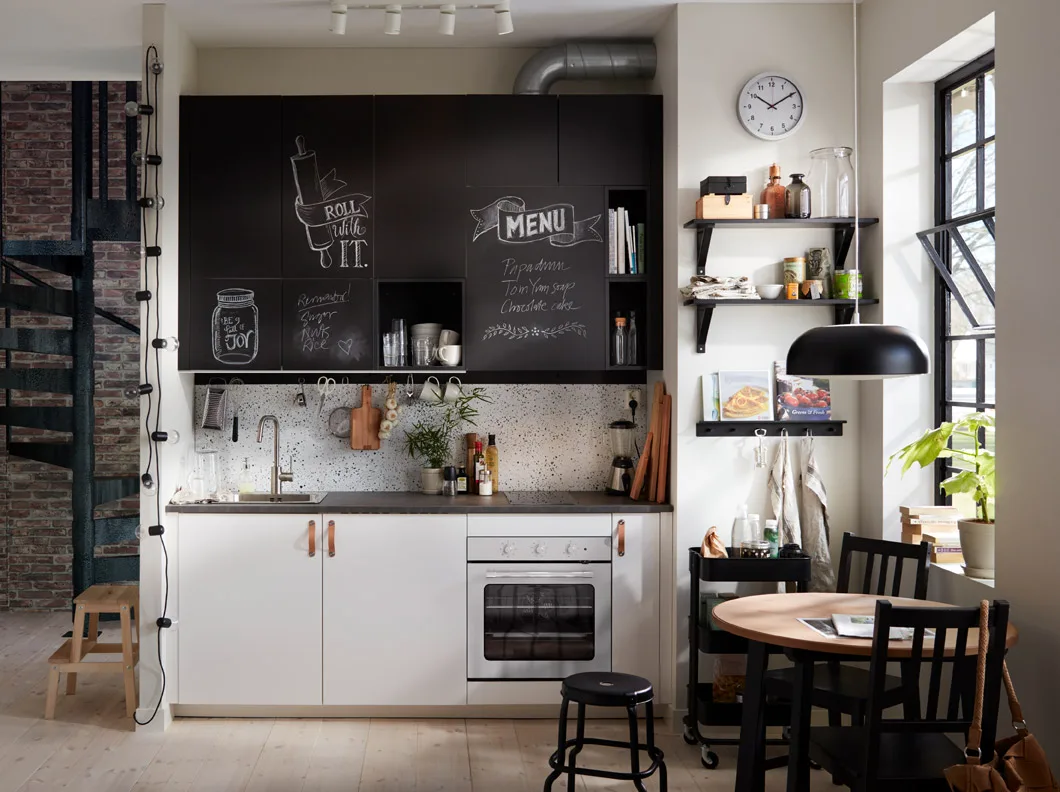 Small black and white kitchen with chalk doors inscribed with messages.