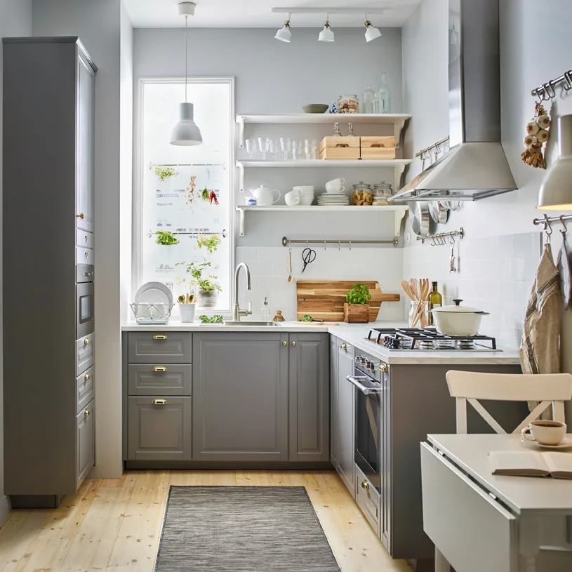 A small sized, traditional-style gray and white kitchen with BODBYN drawer fronts in gray and brass-color ENERYDA knobs and cup handles.